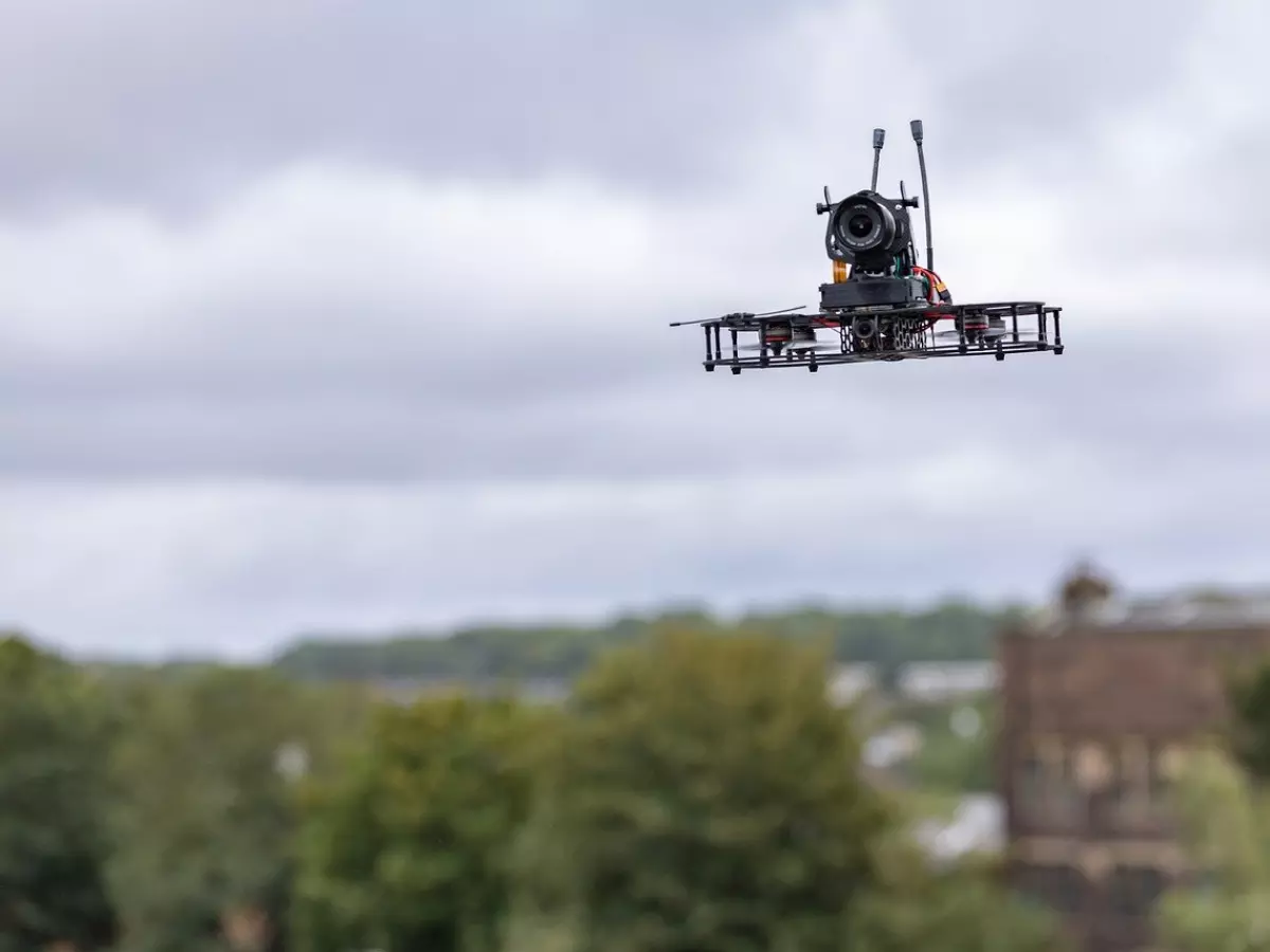 A drone with a camera flying in the air, taken from a low angle.