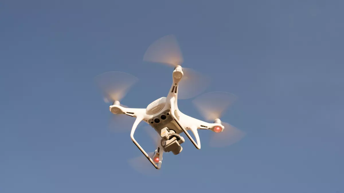 A drone flying in the sky with its propellers spinning.