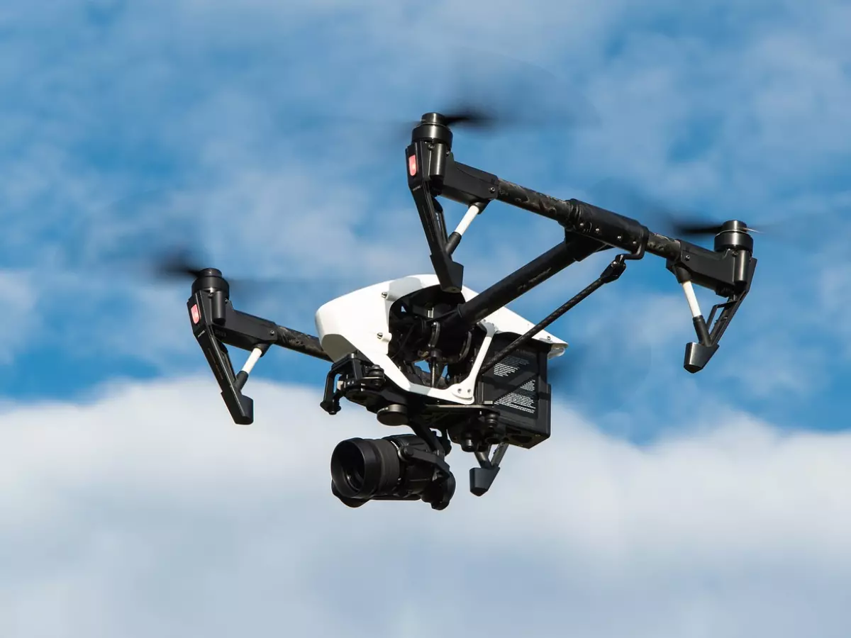 A drone flying in the sky with a blue sky in the background.