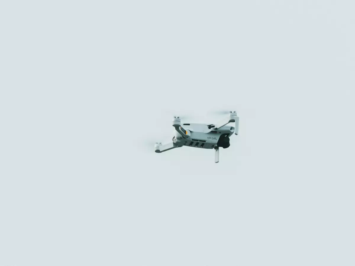 A drone hovering in the air with a white background.