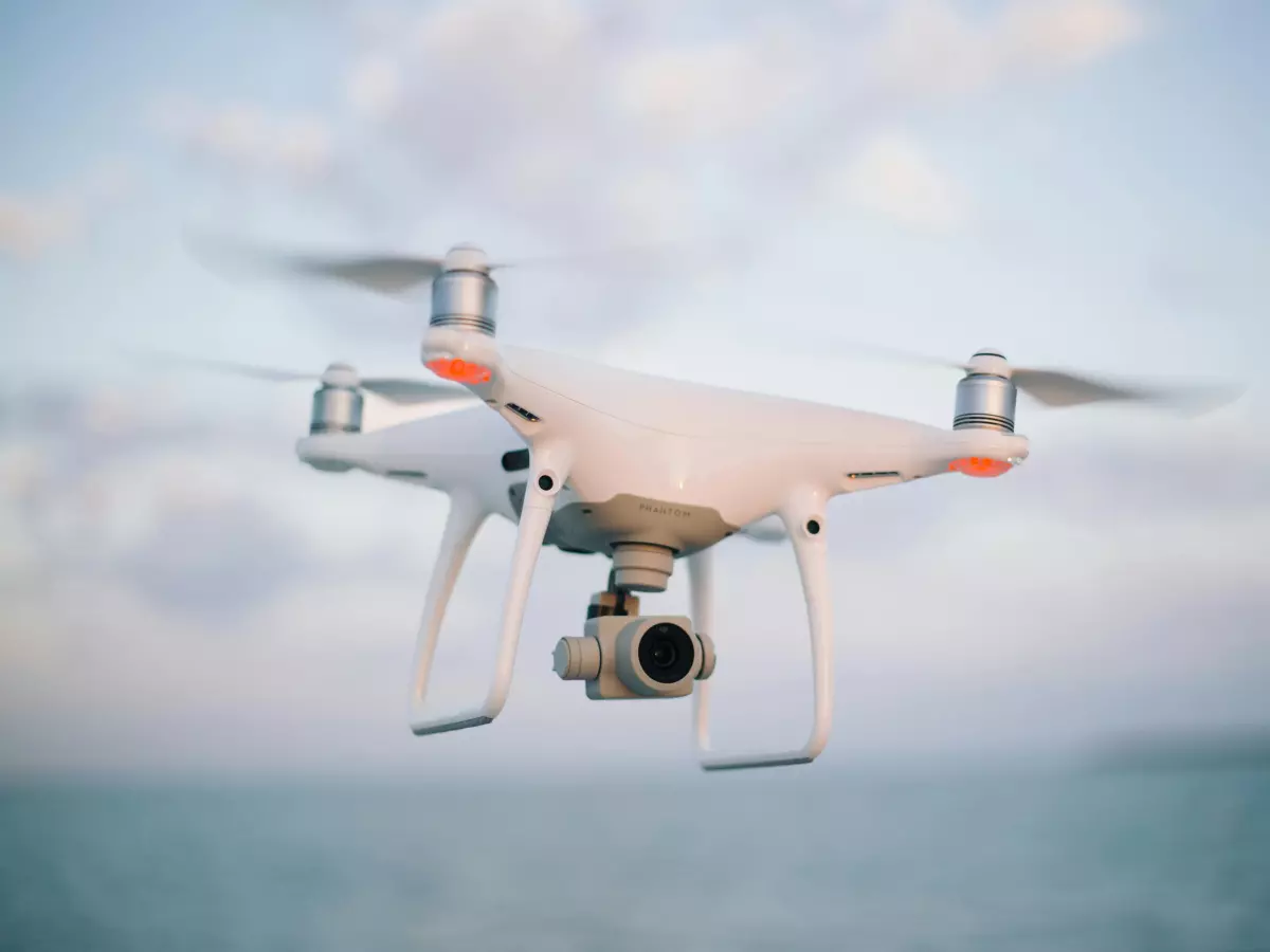 A drone in flight, captured from below, showing its camera lens and propellers.