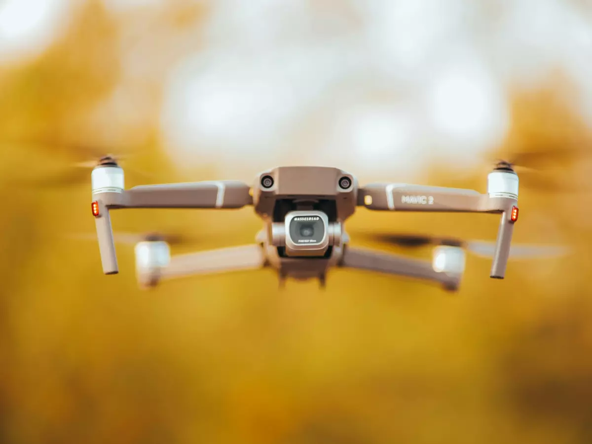 Close-up of a drone in flight against a blurred background of autumnal colors.