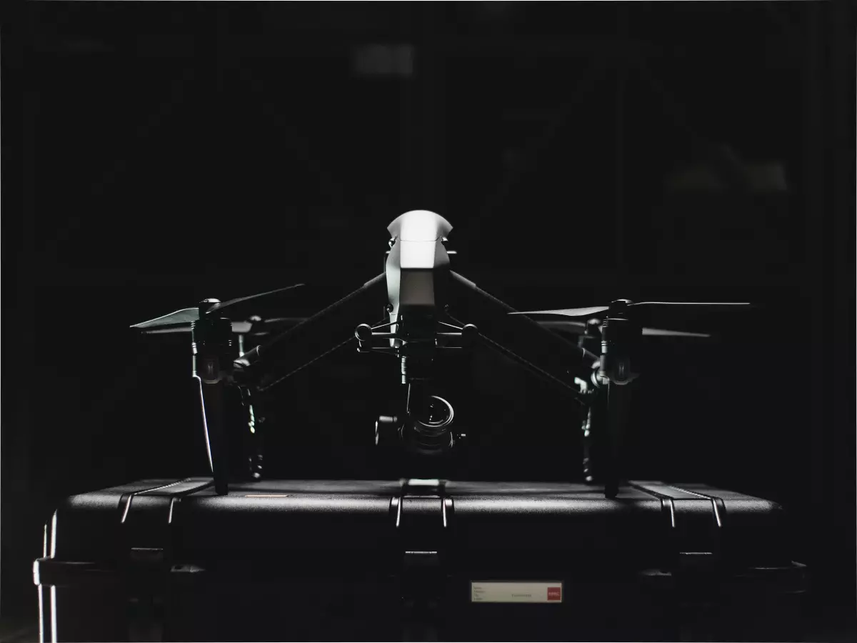 A drone in flight against a dark, stormy sky. The drone's propellers are blurred, suggesting high speed.