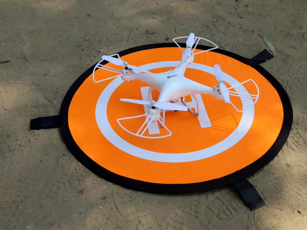 A white drone landing on a designated landing pad. 