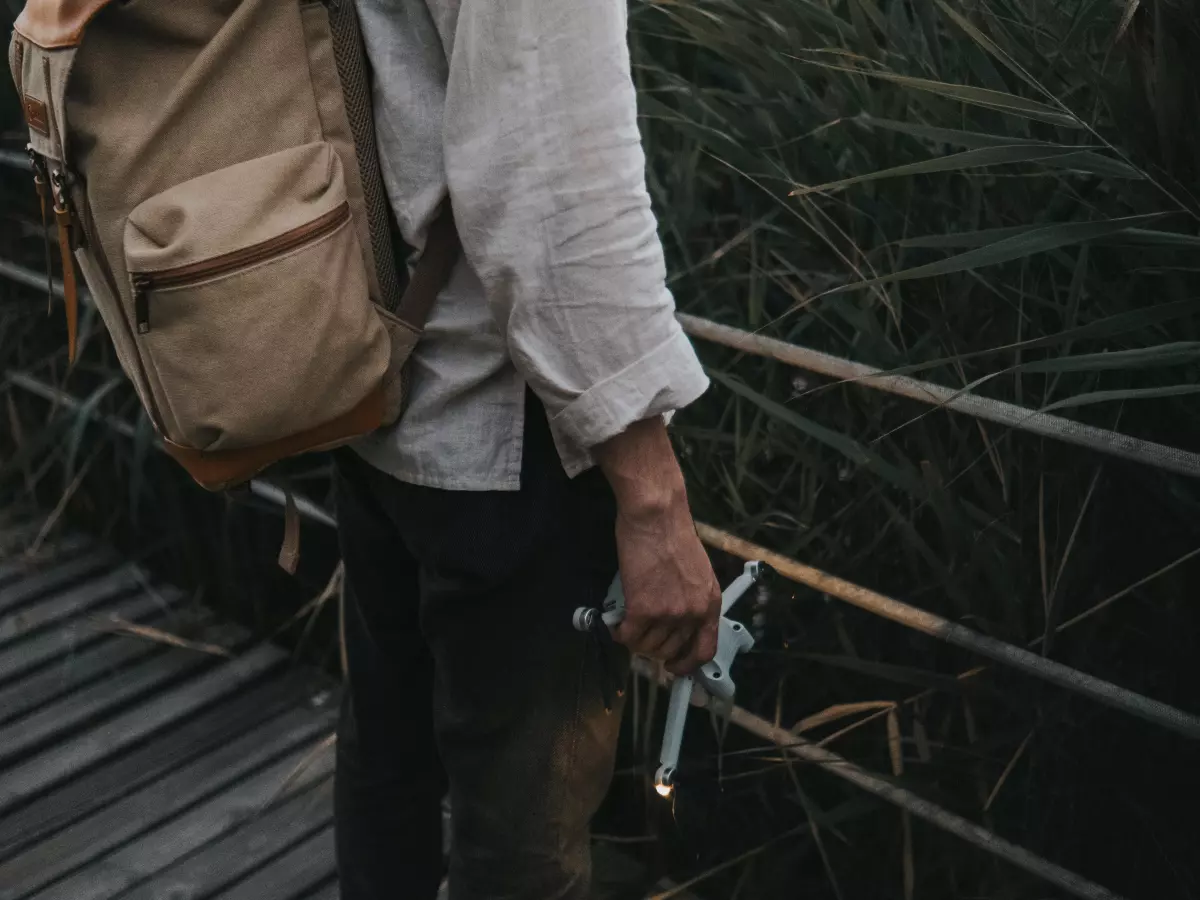 A man with a beard is inspecting a small gadget with a  concentrated look.