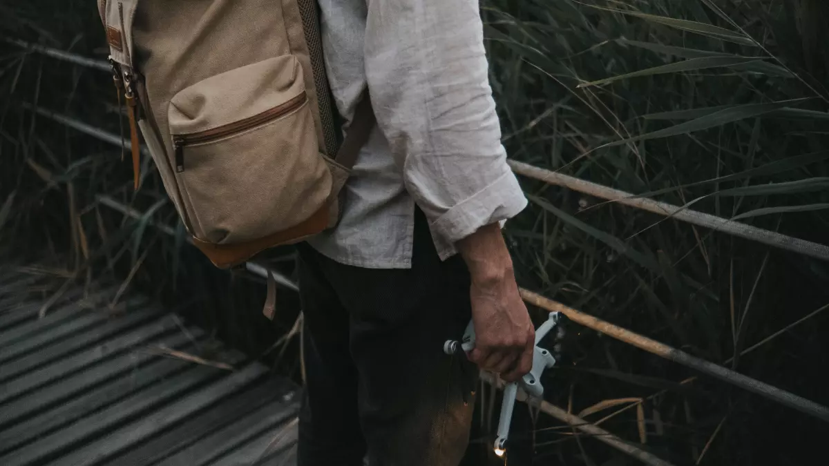 A man with a beard is inspecting a small gadget with a  concentrated look.