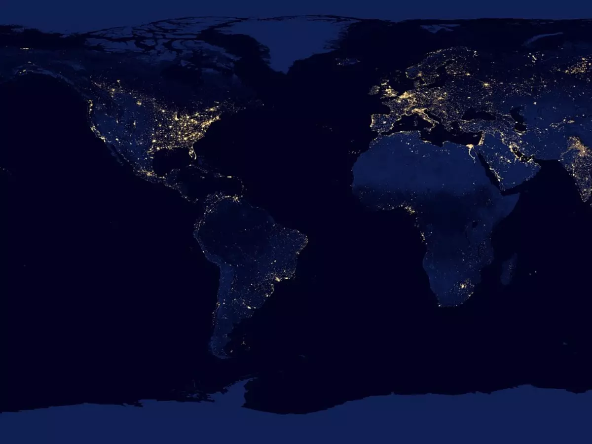 A satellite view of Earth at night, showing the lights of cities around the world.