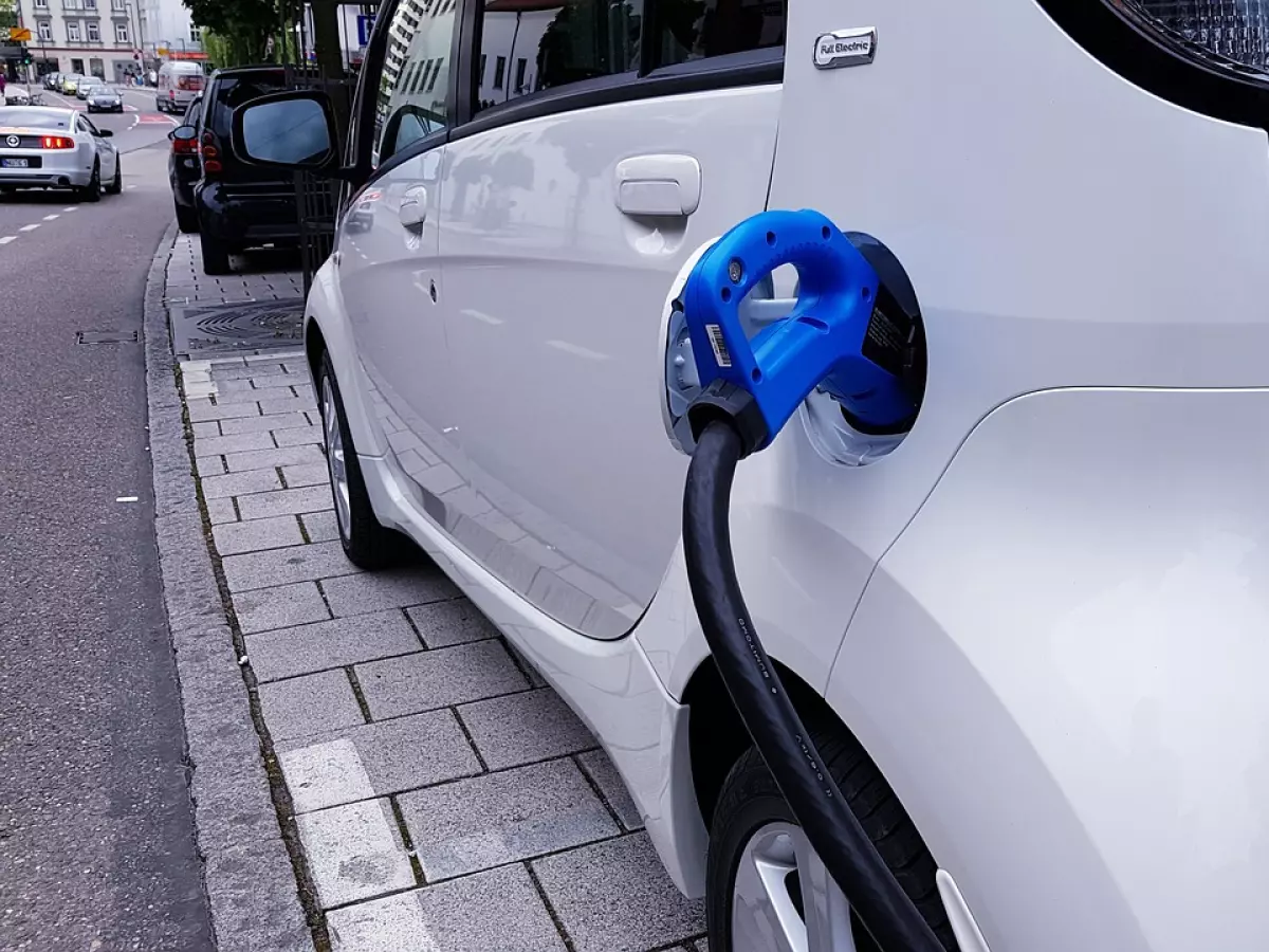 A white Citroen electric car being charged with a blue charging cable.