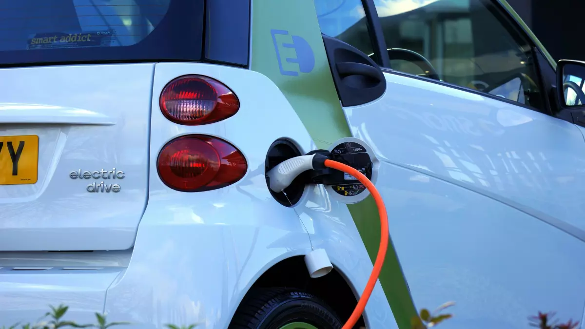 An electric vehicle being charged with an orange cable.