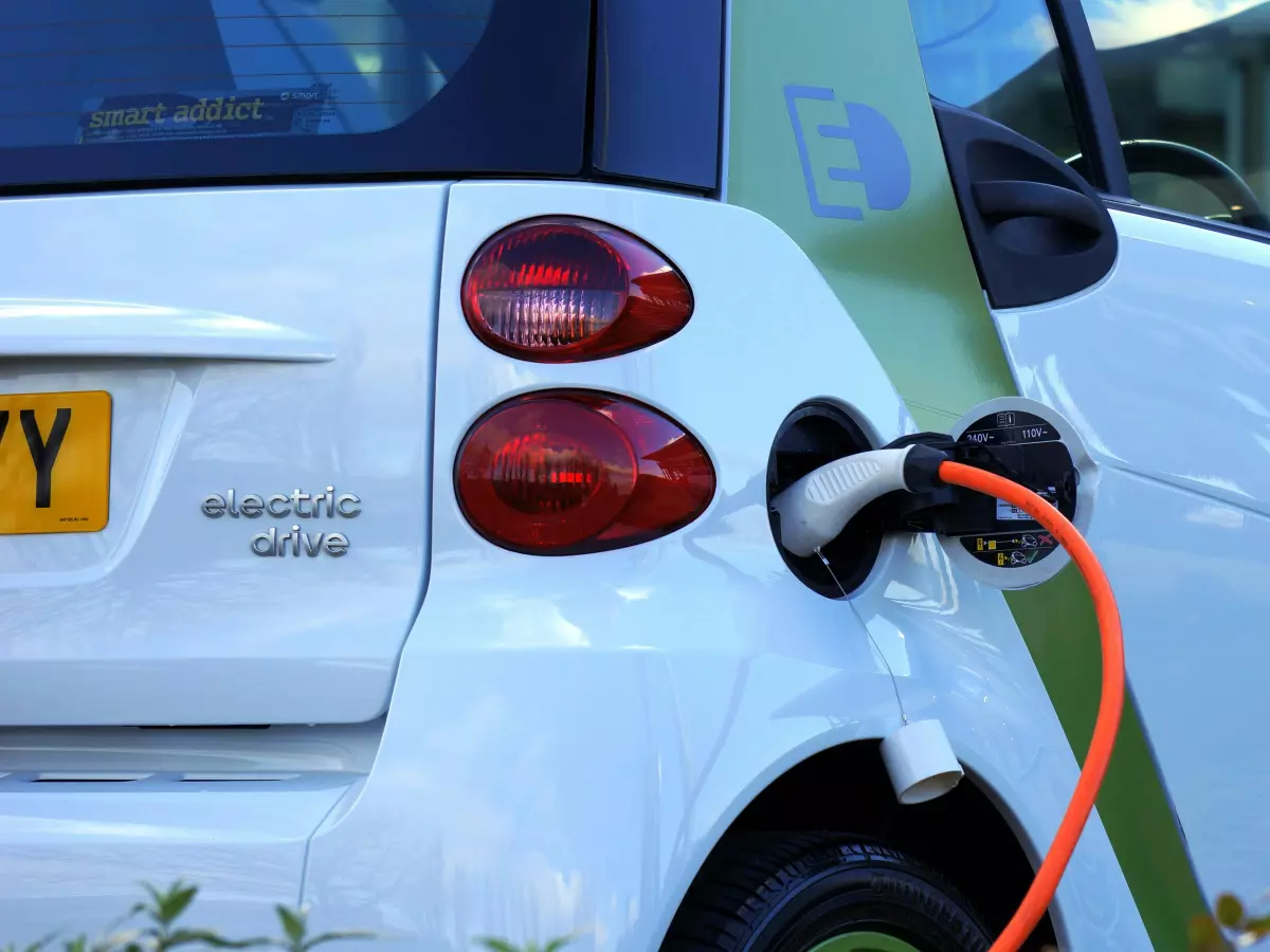 An electric vehicle being charged with an orange cable.