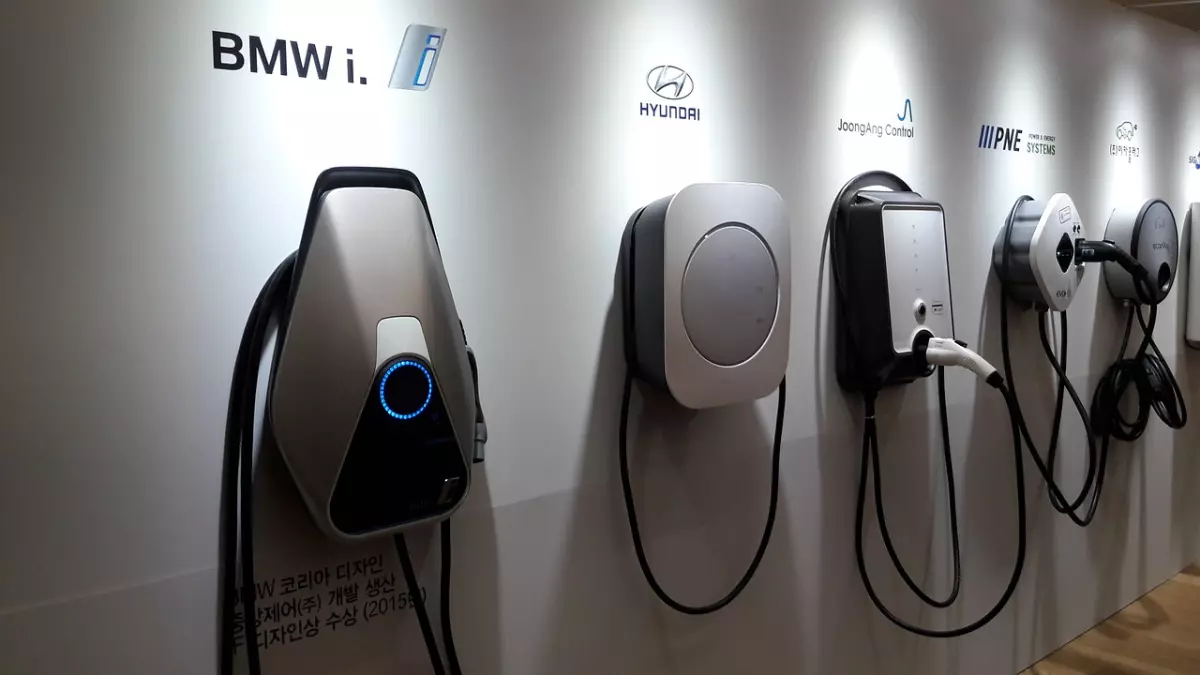 A display of different electric vehicle charging stations from various manufacturers like BMW, Hyundai, and others.