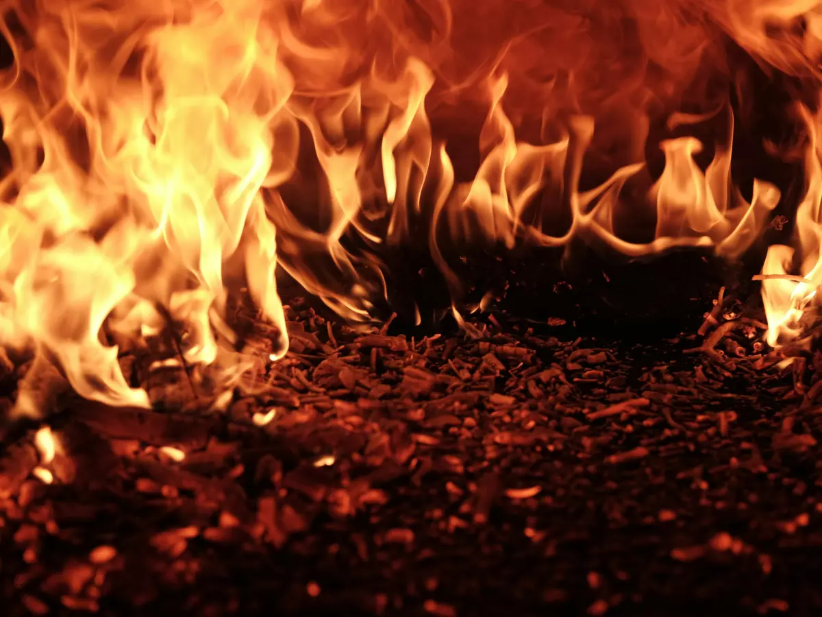 Close-up of intense orange flames engulfing a bed of charcoal embers.