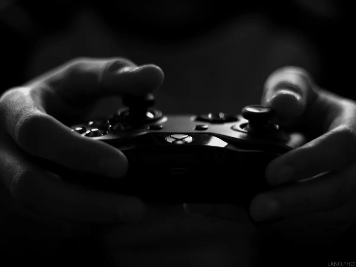 Close-up of hands holding a game controller, with a dark and moody atmosphere.