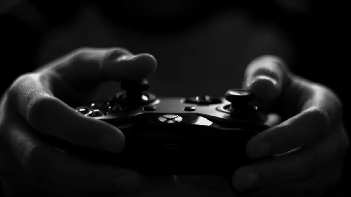 Close-up of hands holding a game controller, with a dark and moody atmosphere.