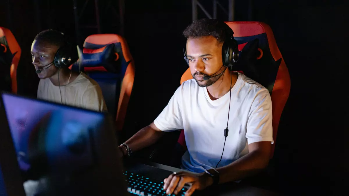 A young man wearing a headset plays a video game on a computer.