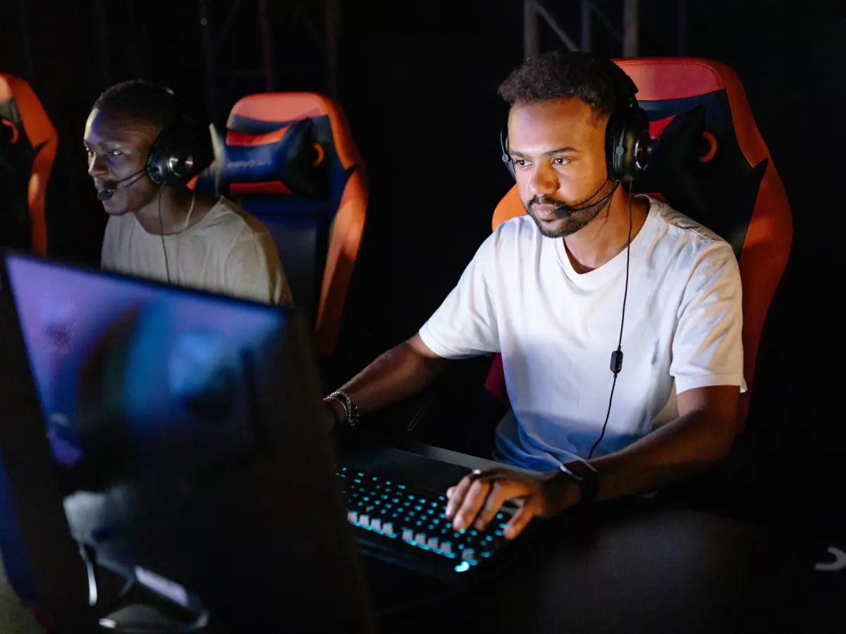 A young man wearing a headset plays a video game on a computer.