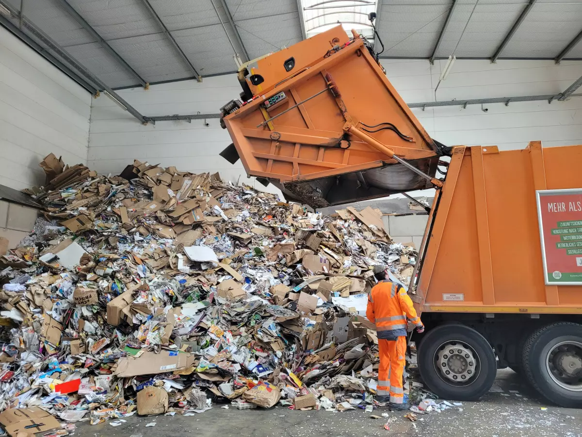 A garbage truck is collecting a large pile of cardboard and other recyclable materials.