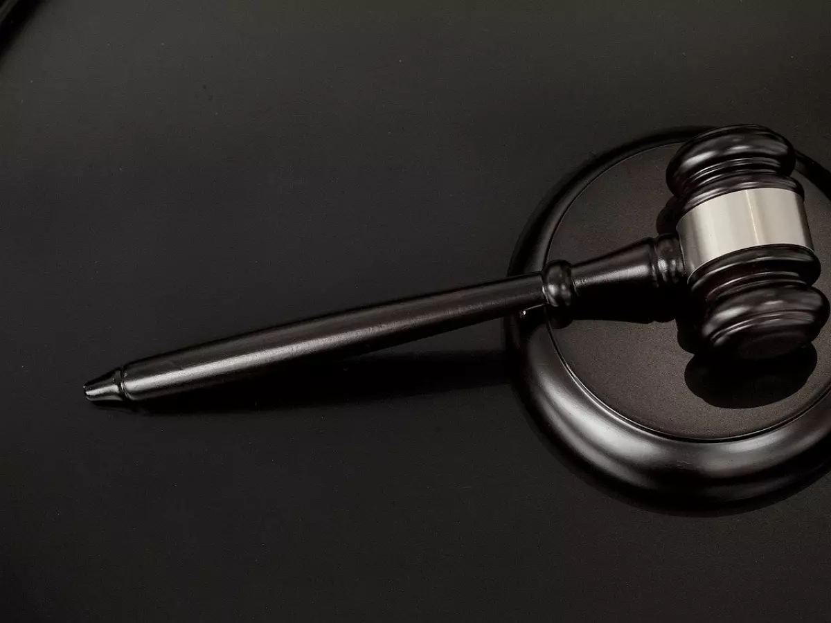 A gavel resting on a block of wood,  against a black background.