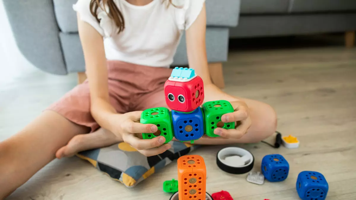 A young girl building a robot out of colorful blocks.