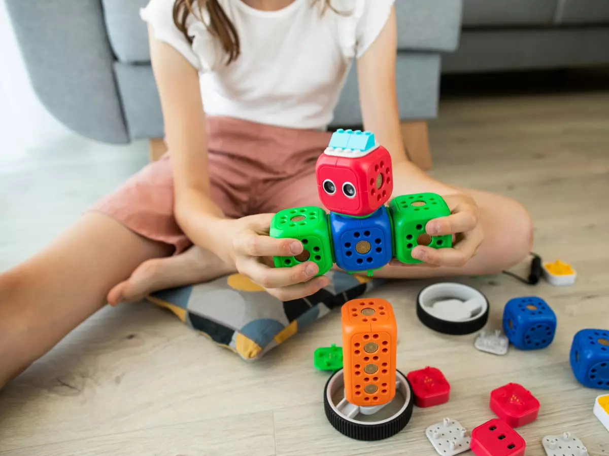 A young girl building a robot out of colorful blocks.