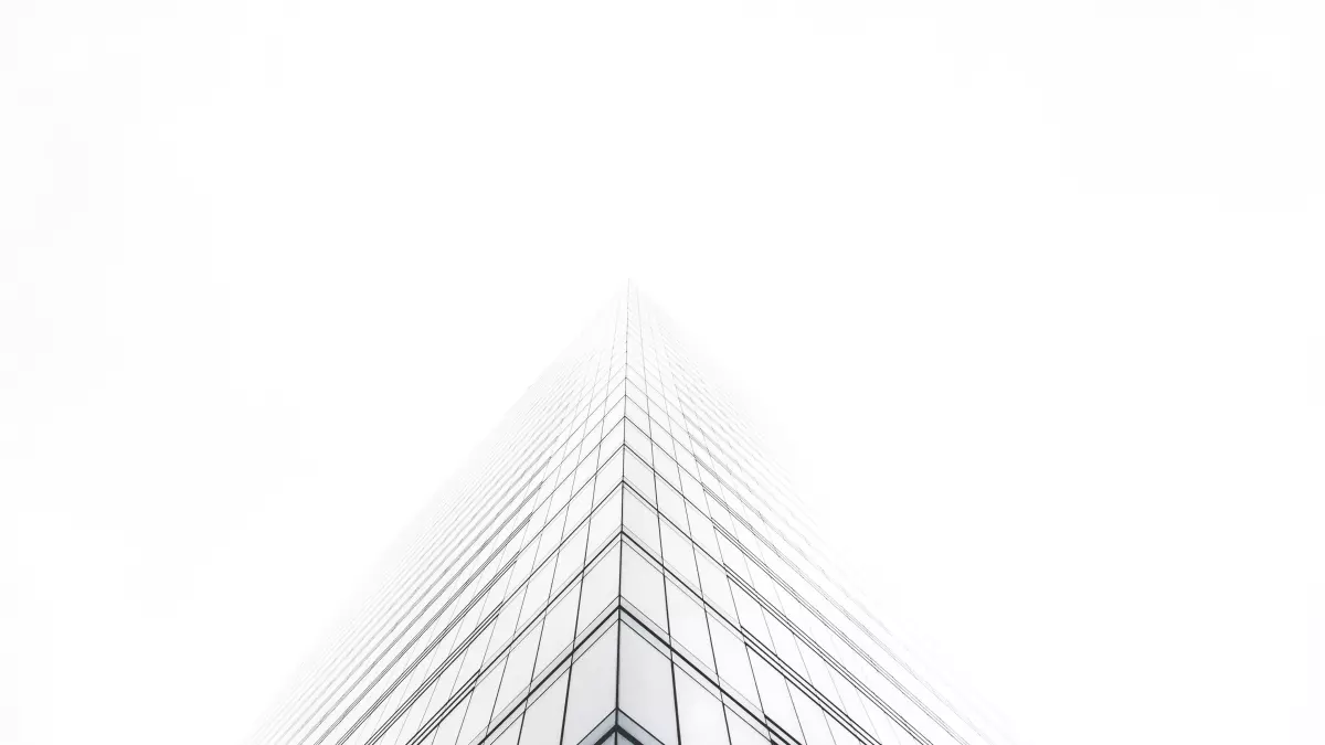 A tall glass building reaching up towards the sky, seen from a low angle.  The building is made of many glass panels.