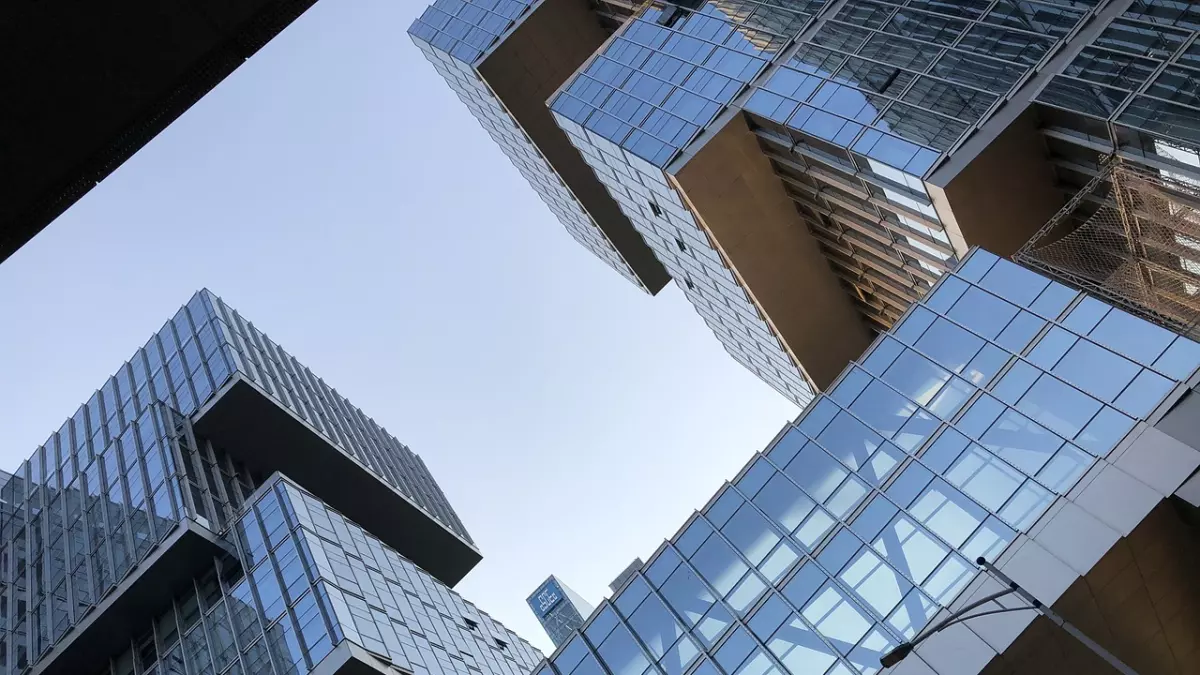 A low-angle shot of tall modern skyscrapers, with a blue sky in the background.