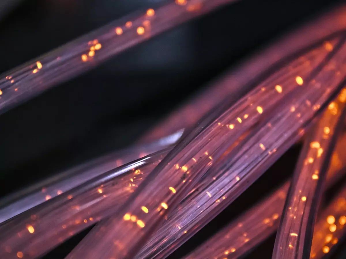 A close up of fiber optic cables glowing with a warm, orange light.