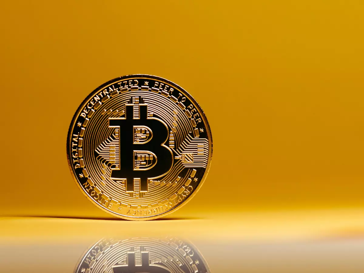 A single Bitcoin coin on a yellow background, with the B symbol clearly visible.