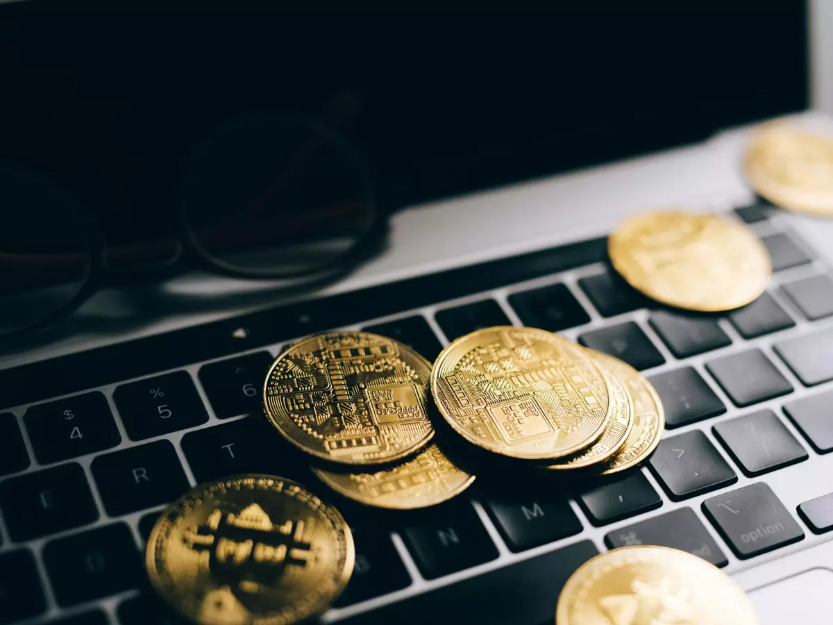 A close-up of a laptop keyboard with gold-colored cryptocurrency coins scattered on it. The image highlights the fusion of technology and finance within the cryptocurrency landscape.