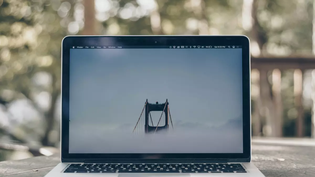 A laptop on a table with a blurry background of nature.