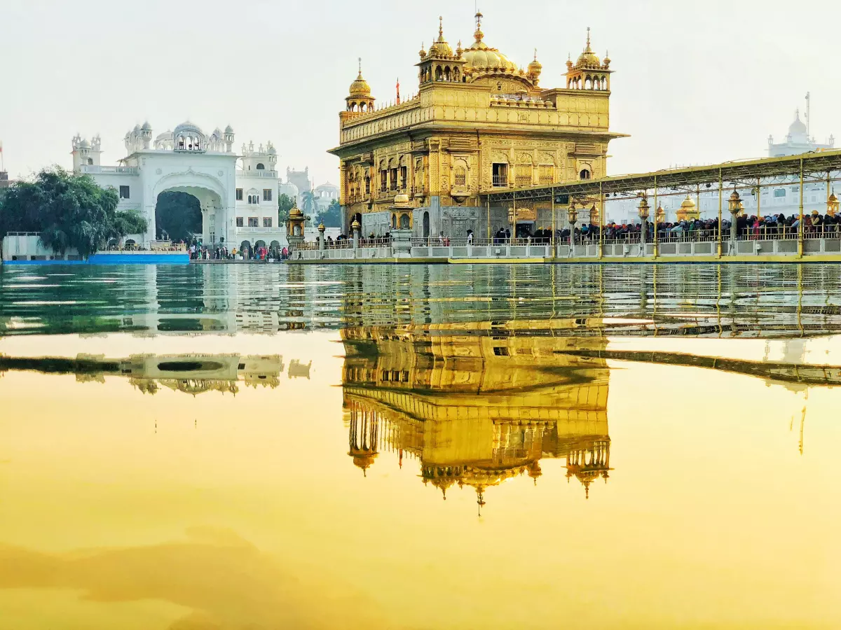 The Golden Temple in Amritsar, India, is reflected in a still pool of water. The temple is a beautiful golden structure, and the reflection creates a sense of depth and mystery.