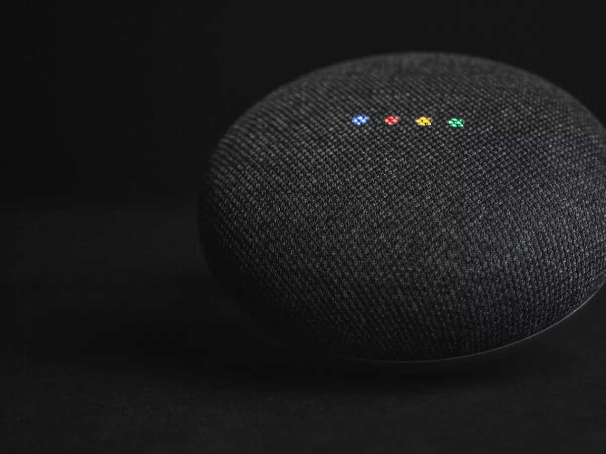 A black Google Home smart speaker with colored lights on the top.