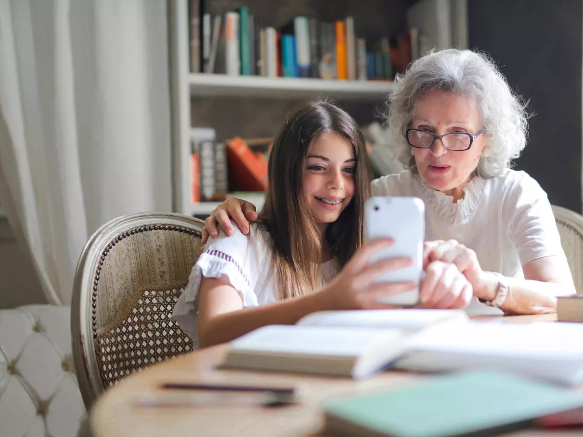 A young woman and an older woman are both looking at a smartphone together.