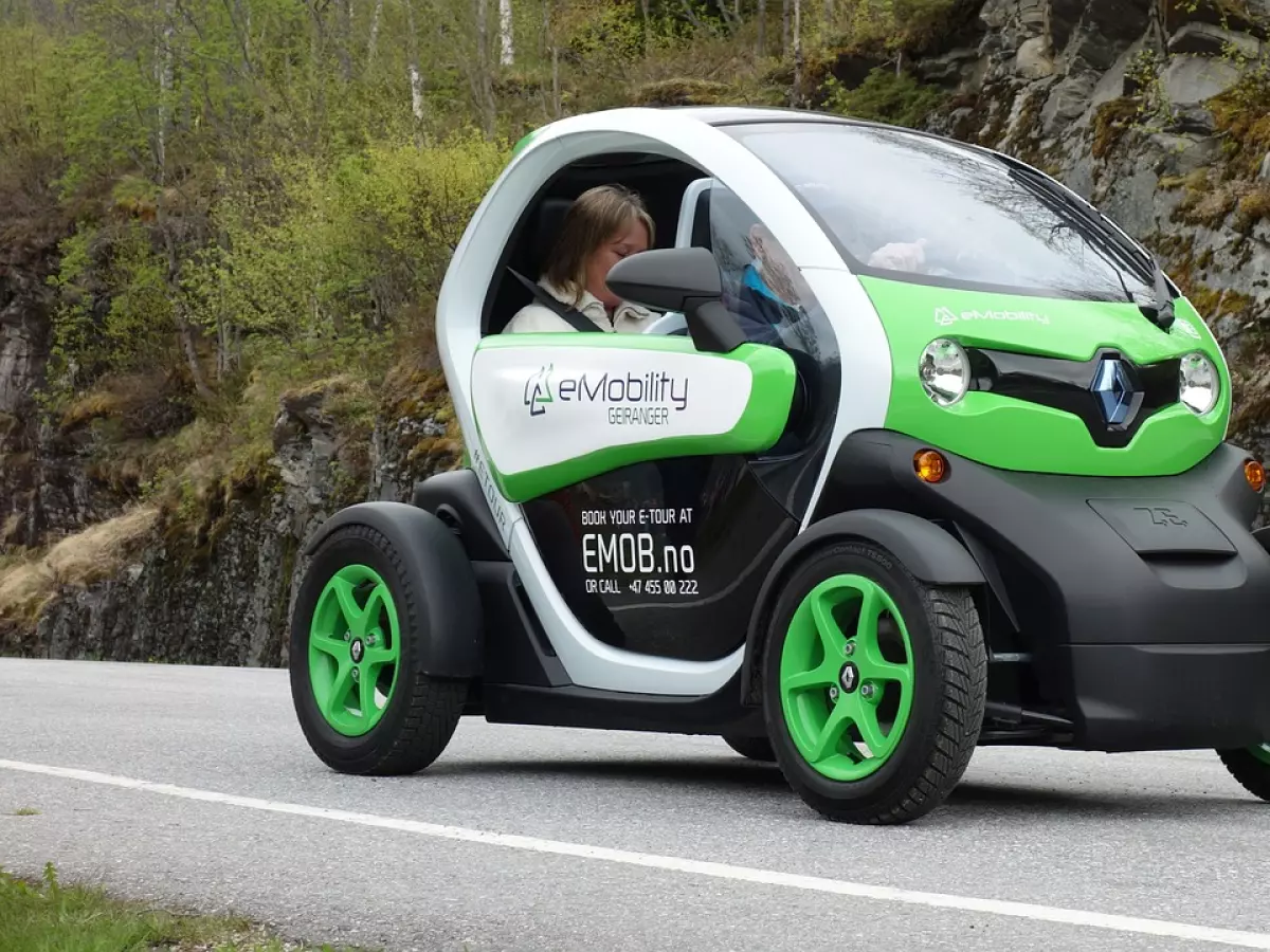 A woman driving an electric car in Norway with a beautiful mountain backdrop.