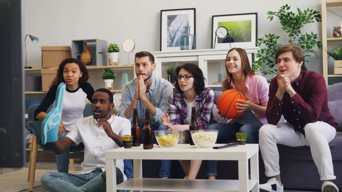 A group of people watching TV together. They are laughing and enjoying each other