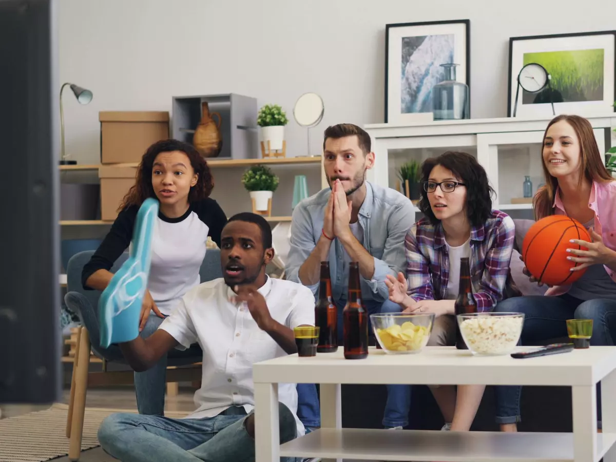 A group of people watching TV together. They are laughing and enjoying each other's company. The image is bright and colorful, and it conveys a sense of fun and excitement.