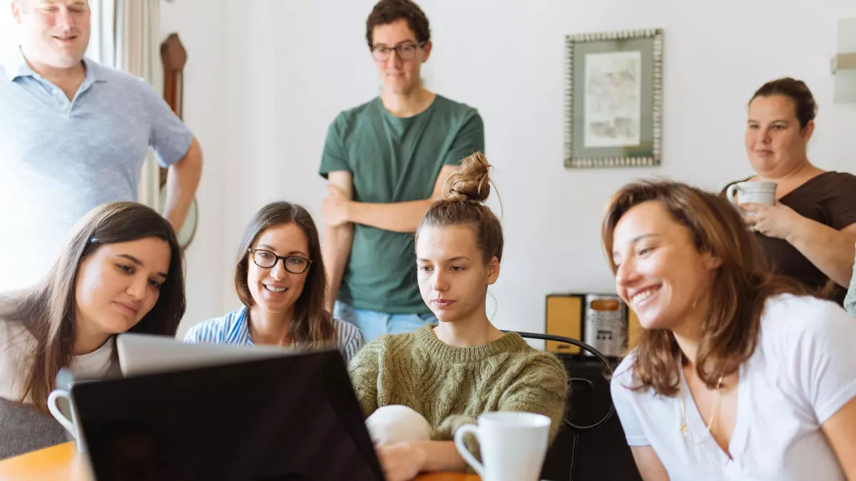 A group of people looking at a laptop in a living room.