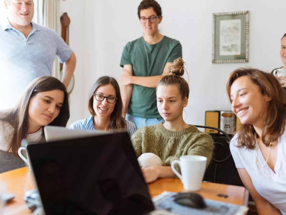 A group of people looking at a laptop in a living room.