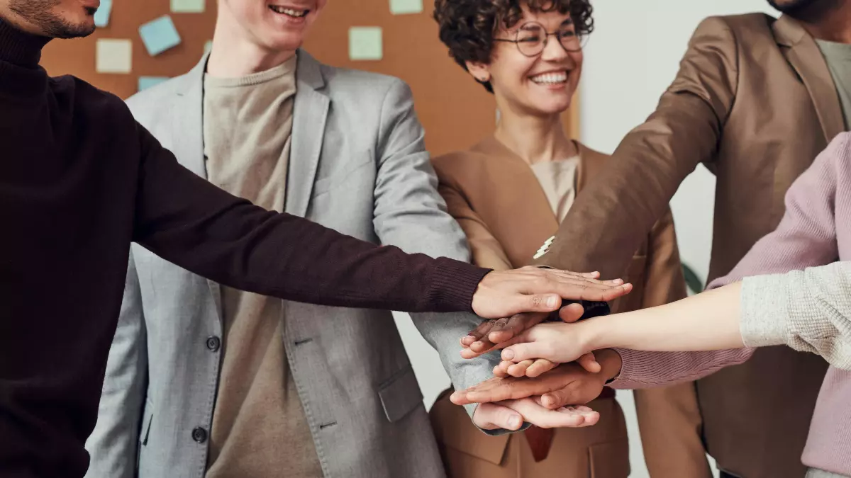 Group of diverse business people putting their hands together in unity, showcasing teamwork and collaboration.