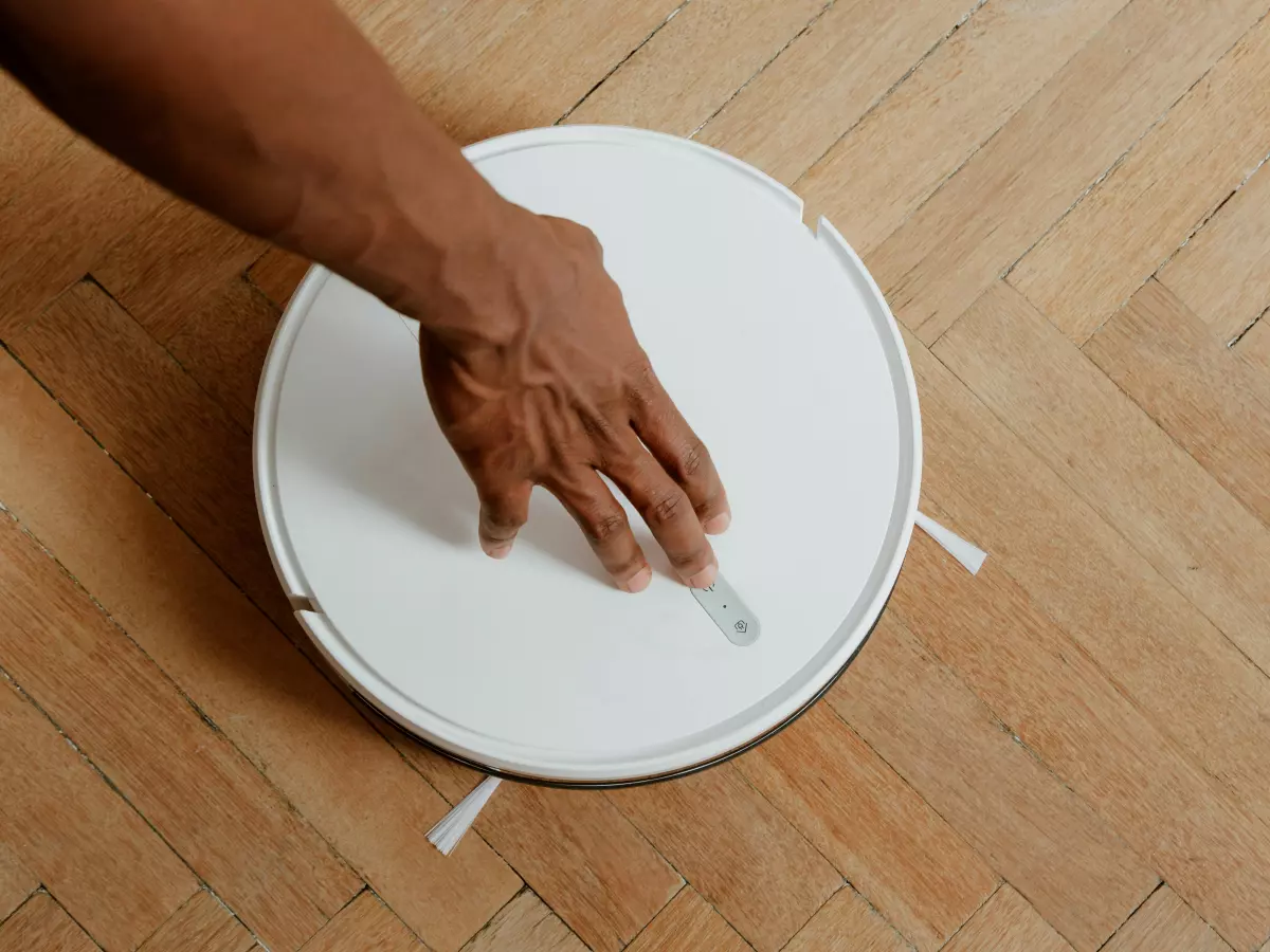 A person is interacting with a robot vacuum cleaner.