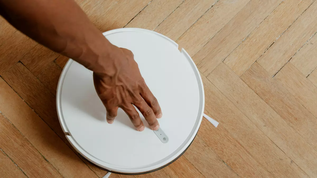 A person is interacting with a robot vacuum cleaner.