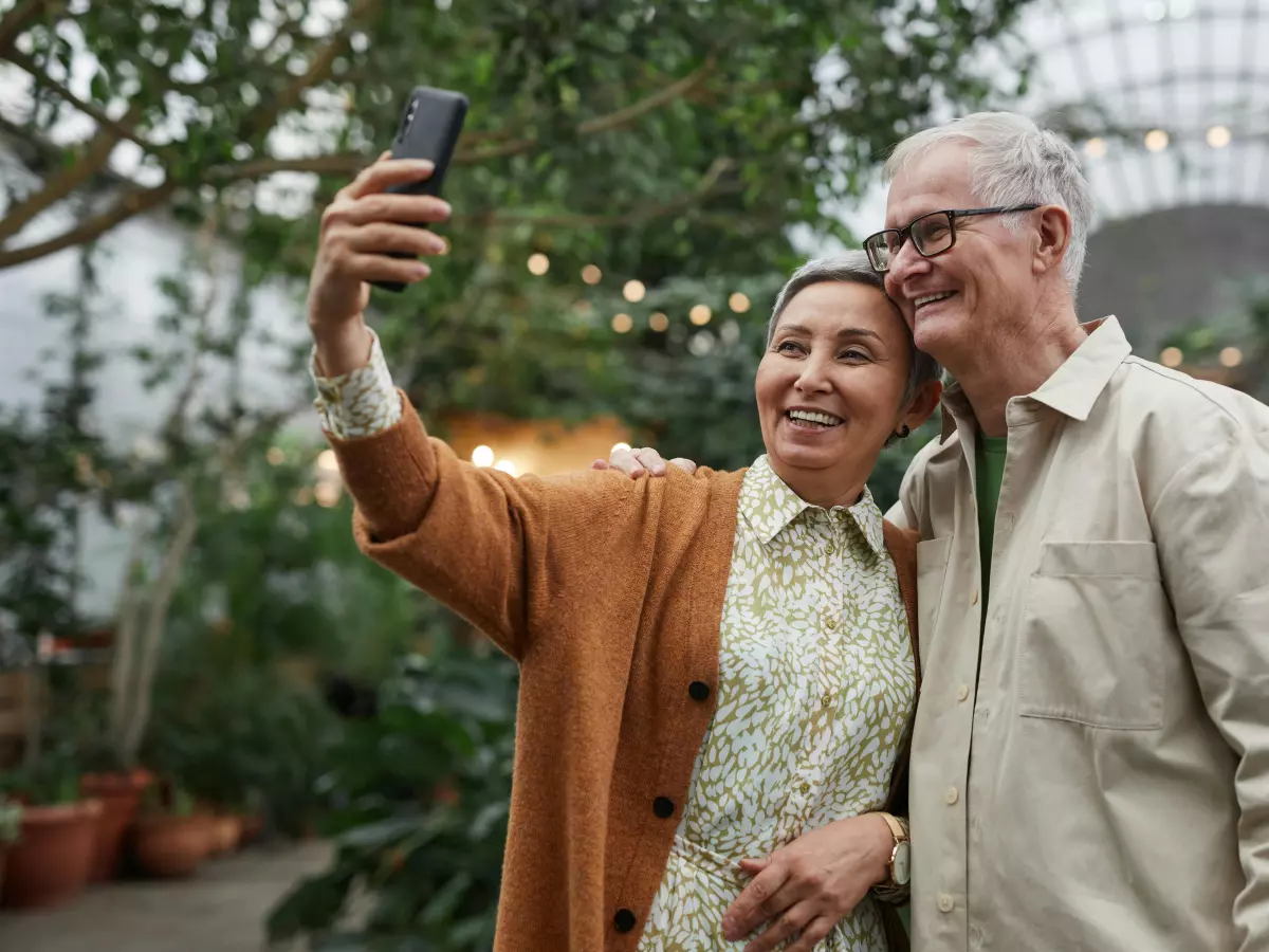 An older couple is taking a selfie in a botanical garden.