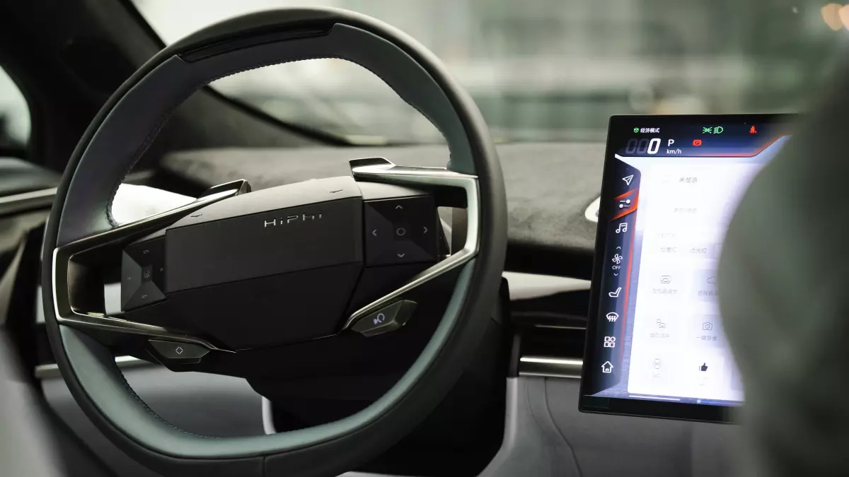 The interior of a modern electric car, showcasing a futuristic steering wheel and a large touchscreen display, likely displaying battery management information and software features.