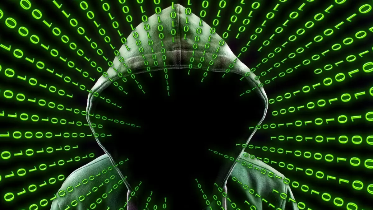 A hooded figure stands in front of a swirling background of binary code, their face obscured by the darkness. The green binary code represents the digital world of hacking and malware, while the hooded figure symbolizes the anonymity of the hacker.