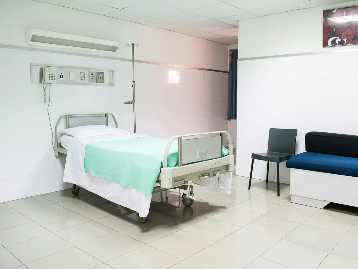 A hospital room with a bed, a chair, and a sofa