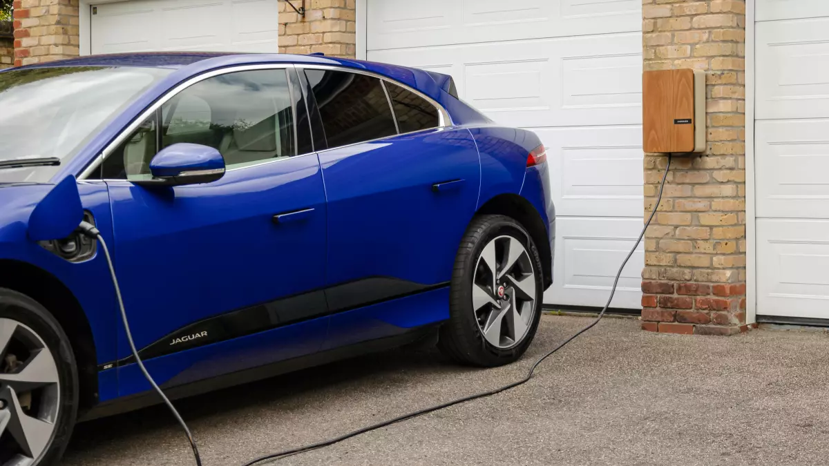 A blue electric vehicle charging at a home charging station.