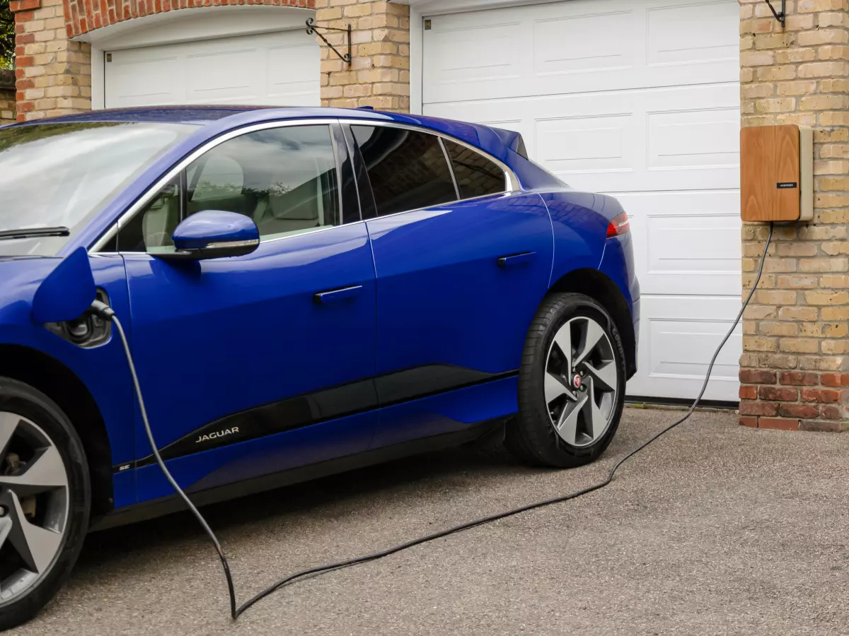 A blue electric vehicle charging at a home charging station.