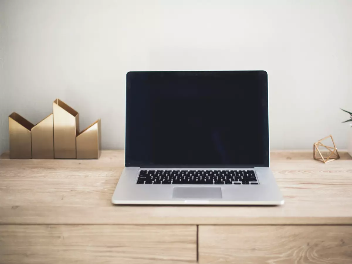 A laptop on a wooden desk with gold decor.