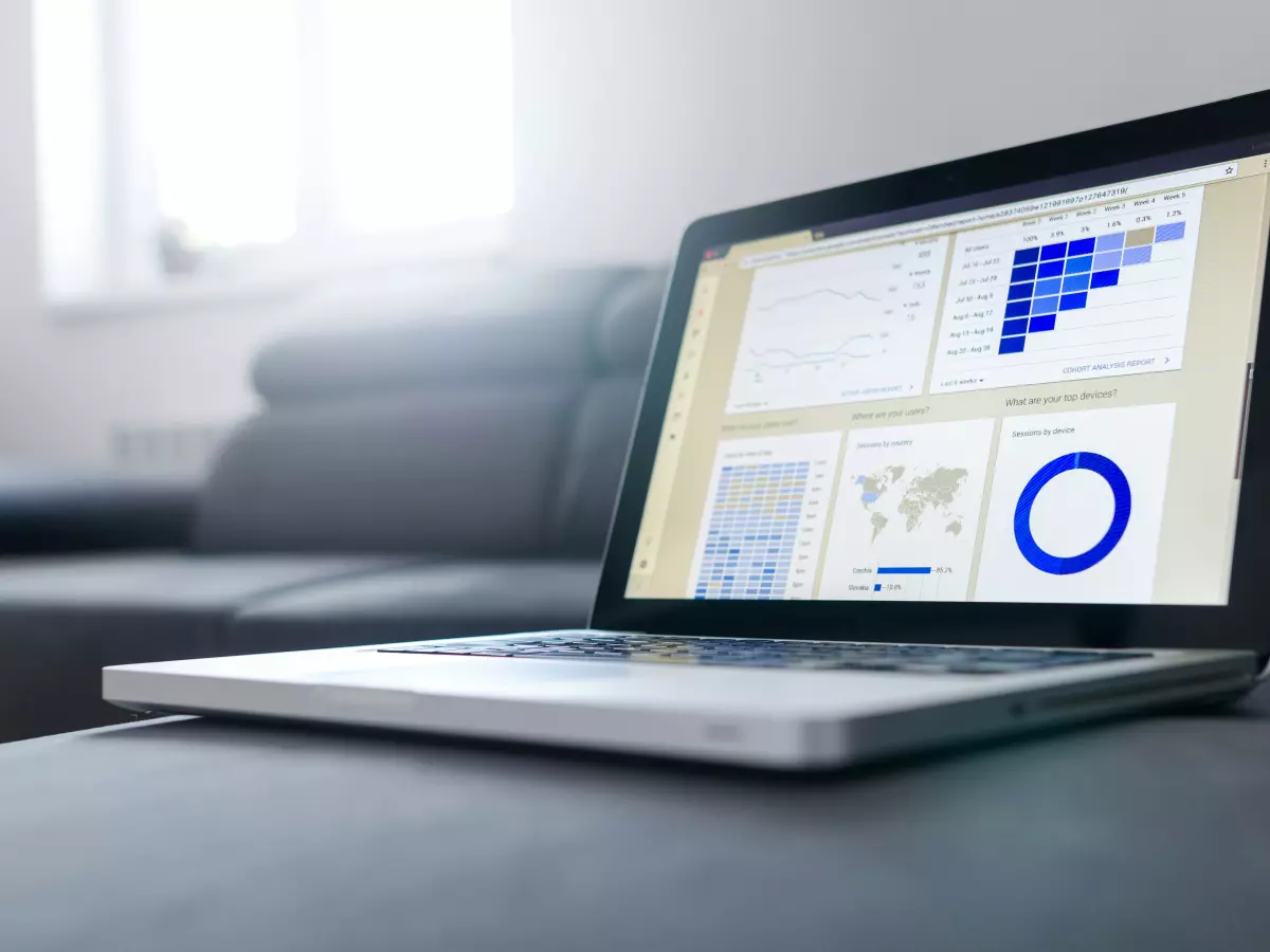 A laptop computer is open on a sofa. The screen displays several charts and graphs, including a world map.