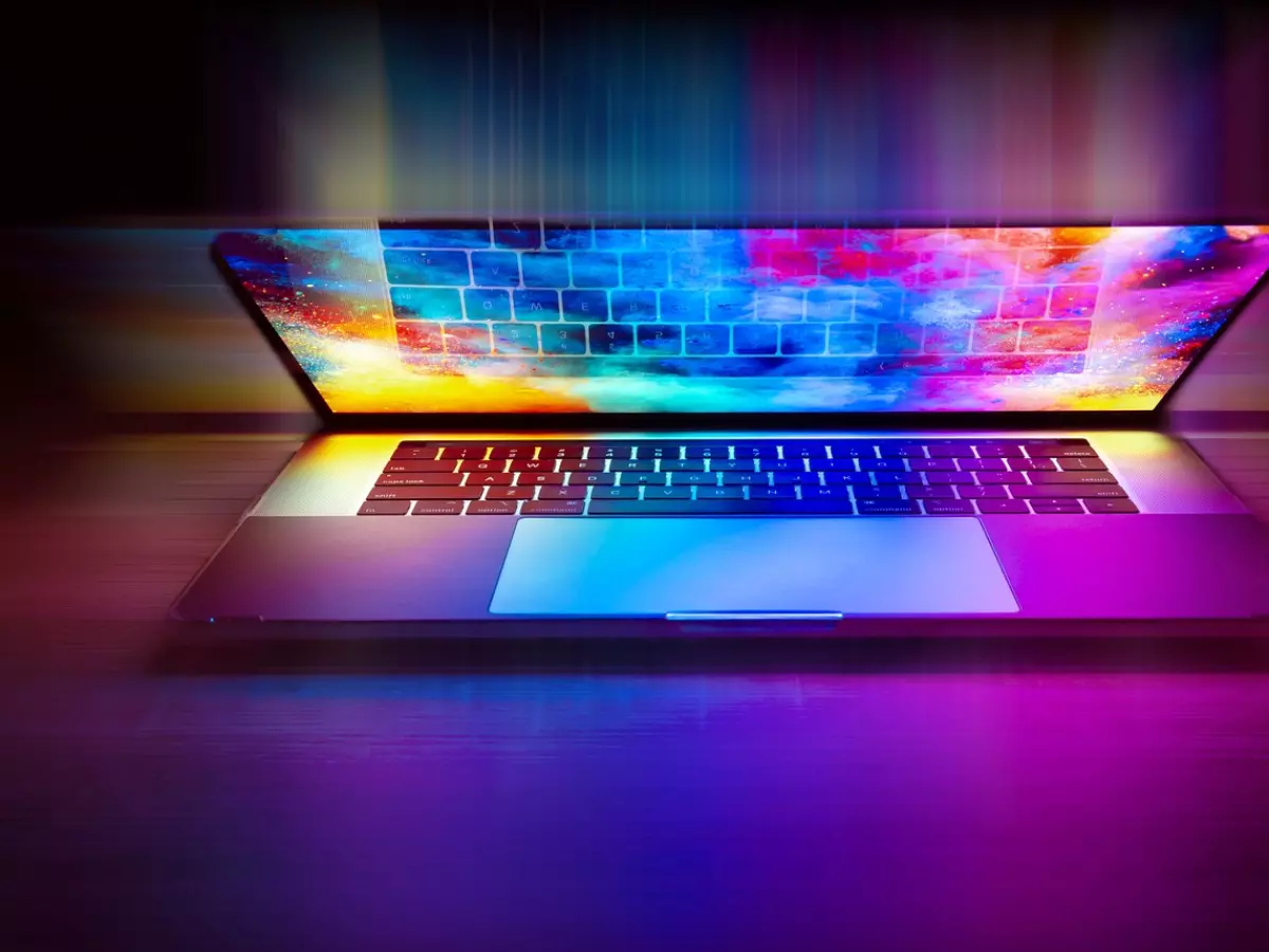 A laptop with a colorful display is on a wooden table.